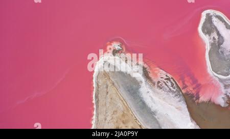 Flying over a pink salt lake. Salt production facilities saline evaporation pond fields in the salty lake. Dunaliella salina impart a red, pink water Stock Photo