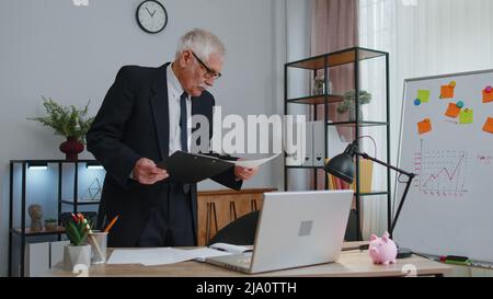 Senior business man examining graphs, analyzing, managing finance documents report at home office Stock Photo