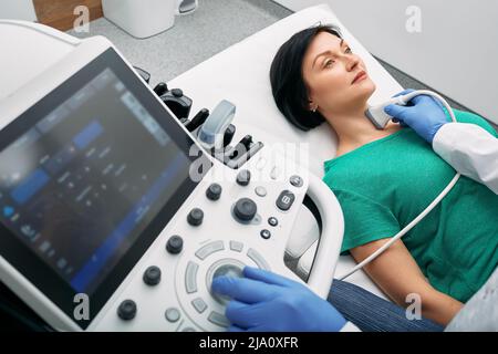 Ultrasound diagnostics of endocrine system and thyroid for woman. Female patient receives thyroid diagnostics. Treatment of thyrotoxicosis and hypothy Stock Photo