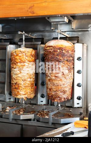 Two rotisseries in a Grecian kebab house cooking lamb and chicken meat  . The meat will be used in kebabs or Greek gyros or souvlaki from the premises. Stock Photo