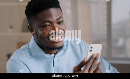 Happy young african american guy businessman handsome entrepreneur man worker hold smartphone talk by video call greeting have virtual meeting chat Stock Photo