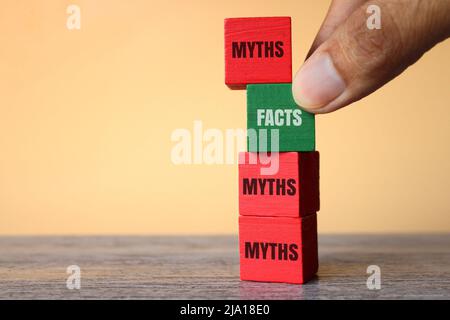 Hand pick wooden cube with text FACTS over MYTHS. Facts vs myths concept. Stock Photo