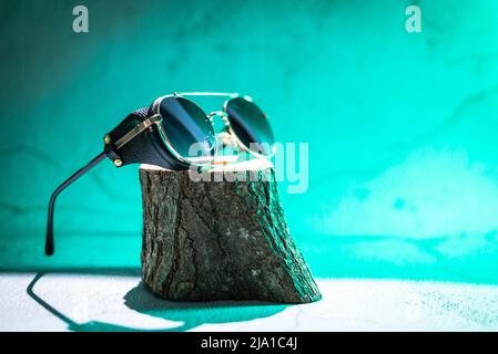 Vintage sunglasses on wooden stand on green background Stock Photo