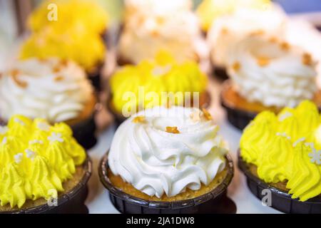 Cupcakes with cream and sprinkles in candy shop window. Selective focus, focus on the foreground and blurred background, copyspace. Stock Photo