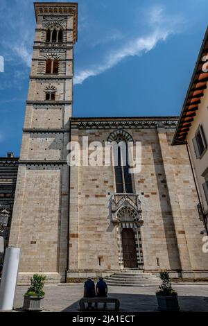 Two people sitting on a bench in the historic center of Prato, Italy, with the cathedral in the background Stock Photo