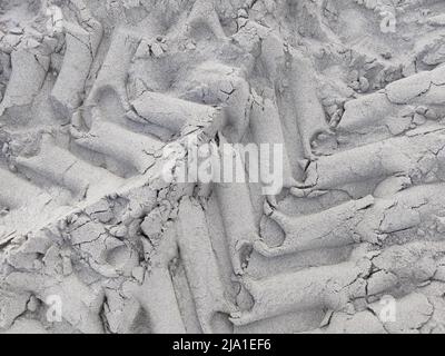 Textured pattern of car tires on gray sand, top view. Close-up Stock Photo