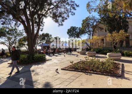 Valletta, Malta - APRIL 29, 2019: people in a cafe enjoy a pleasant evening and sunset. Upper Barrakka Gardens. Sunny calm awesome sunset. Trees in tu Stock Photo