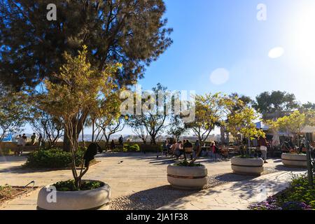 Valletta, Malta - APRIL 29, 2019: people in a cafe enjoy a pleasant evening and sunset. Upper Barrakka Gardens. Sunny calm awesome sunset. Trees in tu Stock Photo