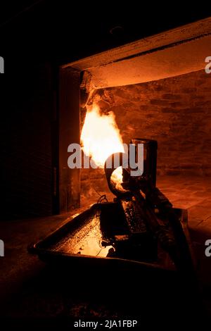 Close-up of a fire cannon warms up a brick oven with a huge flame for further baking in it. Vertical photo Stock Photo