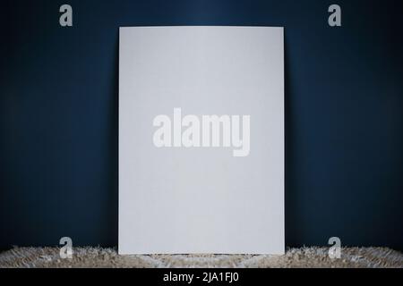 A white sheet of paper stands vertically on a light carpet and an isolated dark background Stock Photo