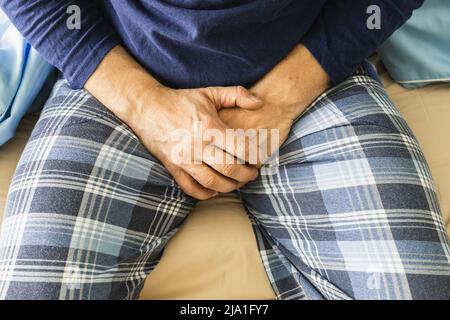 Man sitting in bed and holding his abdomen, Concept of health of sick prostate and problems with urination Stock Photo