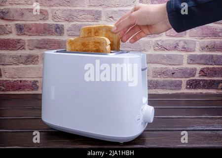 Slices of great toast coming out of the toaster. Healthy breakfast food and heating technology concept. Stock Photo