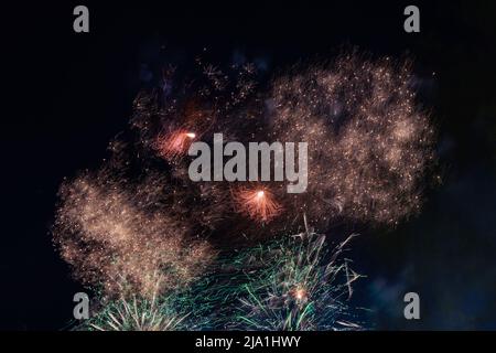 Bright and beautiful sparks of festive fireworks in golden and green color, in the night sky. High quality photo Stock Photo