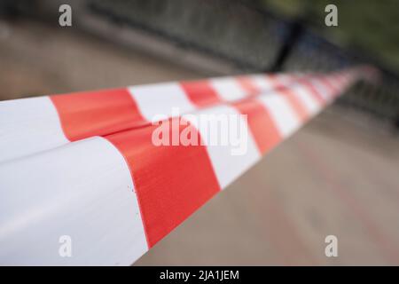 Red and white barrier tape protect a danger place. Selected focus, blurred Stock Photo