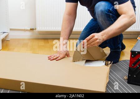 Professional Furniture Assembly Worker Assembles Shelf. Furniture assembly process. DIY Assembling Stock Photo