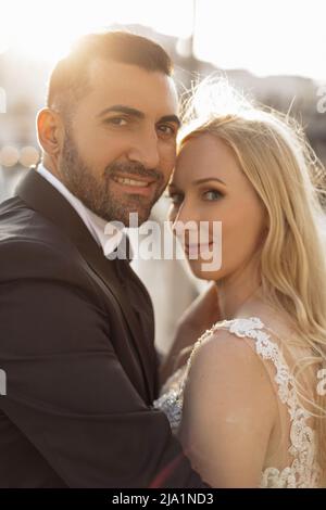 Vertical portrait glad and cheerful romantic married couple, blond woman and black-haired man after wedding, overdressed Stock Photo