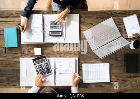 High Angle View Of Two Businesspeople Calculating Bills In Office Stock Photo