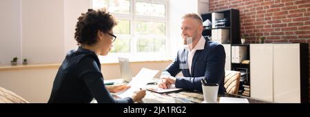 Two Businesspeople Talking With Each Other At Office Stock Photo
