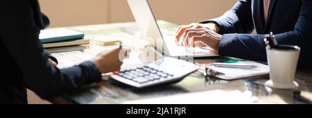 Close-up Of Two Businesspeople Calculating Financial Statement At Desk Stock Photo