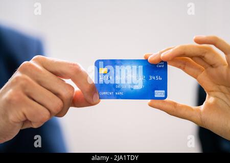 Close-up Of Two Businesspeople Hands Holding Credit Card Stock Photo