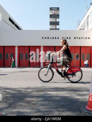 London, Greater London, England, May 14 2022: Lady on a Santander hire cycle aka Borris Bike rides past Chelsea Fire Station on The KIngs Road. Stock Photo