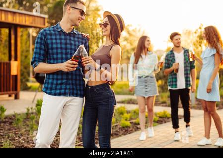 group of friends hang out on the street. They hug each other and walk in the park at sunset. Drinking cold juice.Group of friends walking in the city Stock Photo