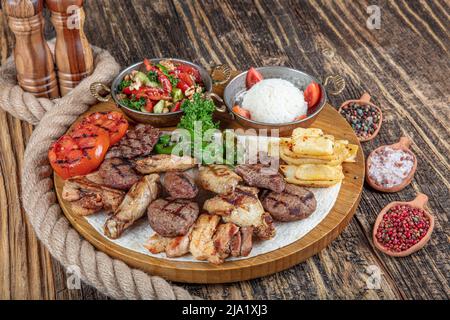 Turkish cuisine, mixed kebab. Meat platter fried on charcoal with spices on a wooden board. Rack of lamb, lamb, kebab, chicken, mushrooms and tomato s