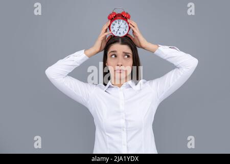 Portrait of young attractive shocked amazed surprised girl hold clock isolated on gray color background. Stock Photo