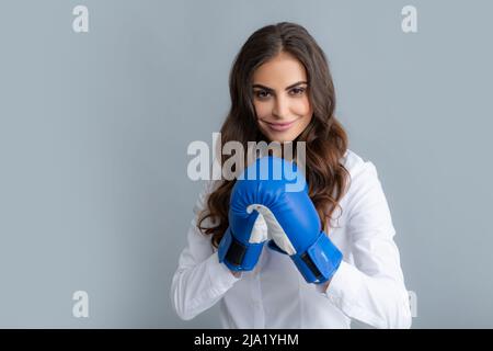 Woman in boxing gloves. Business woman with boxing gloves isolated on gary background. Stock Photo