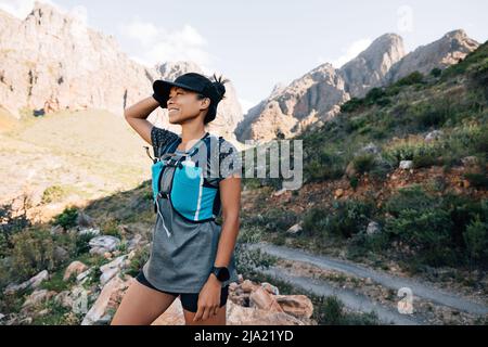 Smiling woman in fitness wear enjoying the view during hike Stock Photo