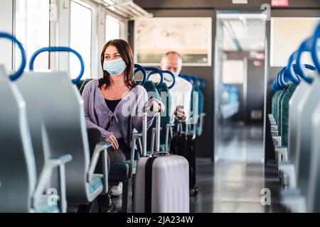 Serious passengers in protective masks during their train day trip Stock Photo