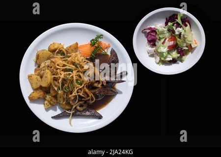 Roasted pork liver with fried onions and fried potatoes with mixed salad plate, on black ground, Franconia, Bavaria, Germany Stock Photo