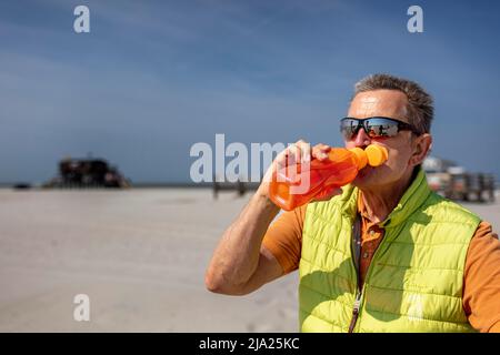 Senior drinking seltzer from a plastic bottle, Sankt Peter Ording, Schleswig Holstein, Germany Stock Photo