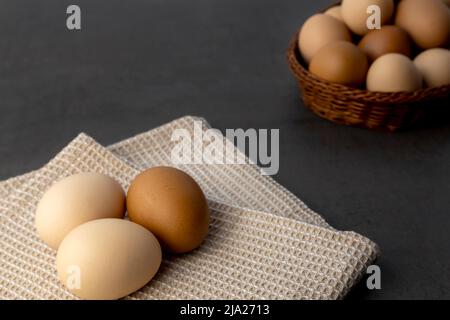 Chicken eggs in a wicker basket on the table. Eggs on a kitchen towel Stock Photo
