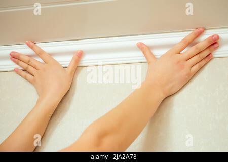 humans hands put a ceiling skirting on the ceiling Stock Photo