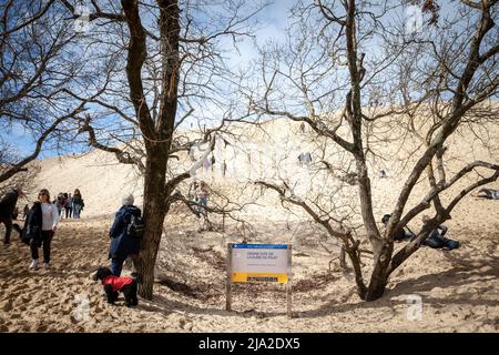 Picture of tourists on Dune du Pilat in front of a sign indicating the entrance to the site. The Dune of Pilat also called Grande Dune du Pilat, is th Stock Photo