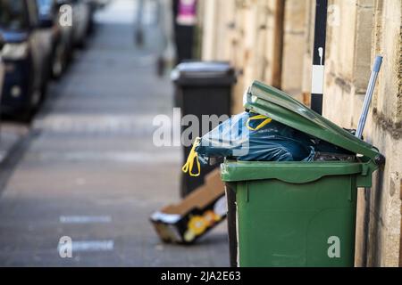 Picture of garbage containers in Bordeaux, France, overflowing with garbage bags falling on the ground. Stock Photo