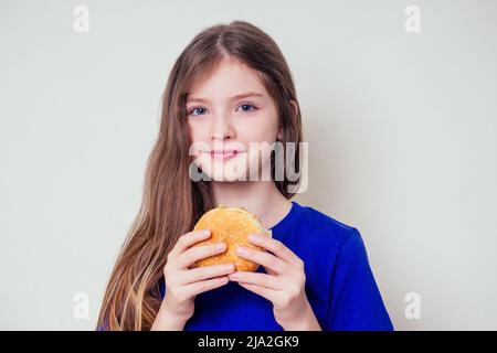 beautiful teenager girl is eating baked vegetarian burger with vegetables. Child vegan idea healthy eating concept.clear skin perfect teen acne Stock Photo
