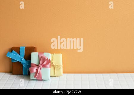 Colorful gift boxes on white table. orange wall background. copy space Stock Photo