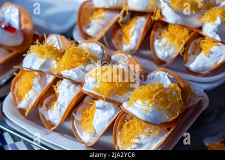 Delicious Thai street dessert, Kanom Buang, Thai Crispy Pancake or Thai Crepe, with varieties of fillings such as sweet white custard cream and golden Stock Photo