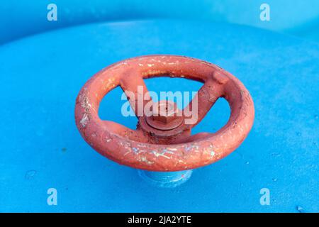 Red valve on the blue pipe. Valve with wheel handle. Industrial gear. Close-up Stock Photo
