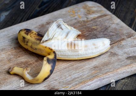 old blackening banana on a cutting board, perishable banana fruit food Stock Photo