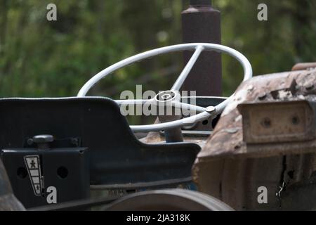 The steering wheel of an old tractor seen from close up. Side view with steering wheel, control panel, gearbox, handbrake and adjustable seats. Stock Photo