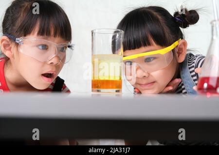 Children are learning and doing science experiments in the classroom. Two little sisters playing science experiment for home schooling. Easy and fun s Stock Photo