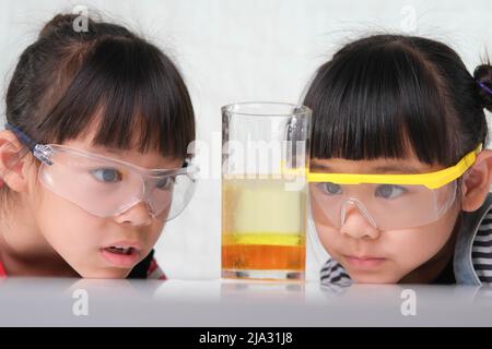 Children are learning and doing science experiments in the classroom. Two little sisters playing science experiment for home schooling. Easy and fun s Stock Photo