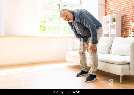 Man Suffering From Knee Pain While Trying To Stand up Stock Photo