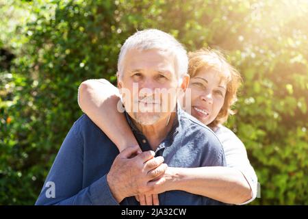 Portrait Of Happy Woman Embracing Her Husband From Behind Stock Photo