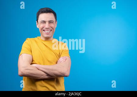 Cheerful man standing with crossed arms and laughing in studio Stock Photo