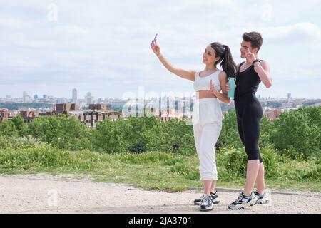 Happy young sport couple taking a selfie while standing at a park. Stock Photo
