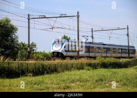 Local commuter train on the track at Moordrecht heading to Rotterdam in the Netherlands. Stock Photo